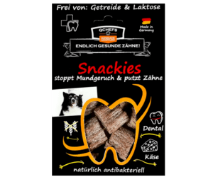 Verpackung der QCHEFS Snackies für Hunde - natürliche antibakterielle Zahnpflege. Schwarze Verpackung mit roter Schrift, auf der steht „Snackies stoppen Mundgeruch und putzen Zähne“. Das Sichtfenster in Form eines Zahns zeigt die knusprigen, käsigen Snacks. Frei von Getreide und Laktose, hergestellt in Deutschland. Ideal zur Unterstützung der Zahngesundheit bei Hunden durch natürliche Inhaltsstoffe.