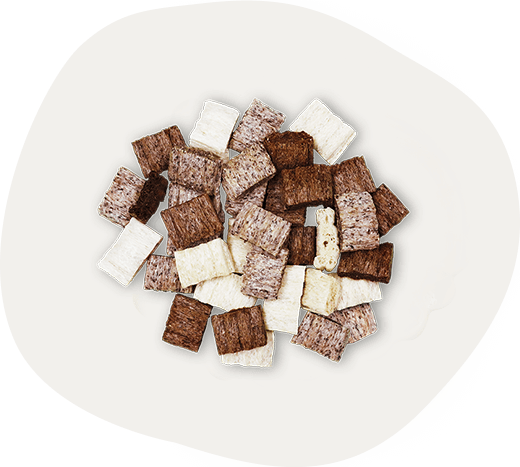 QCHEFS Dreierlei – eine Mischung aus drei verschiedenen gepufften, kleinen, rechteckigen Zahnpflege-Snacks in verschiedenen Farben: hell, mittelbraun und dunkel, mit natürlicher antibakterieller Wirkung.